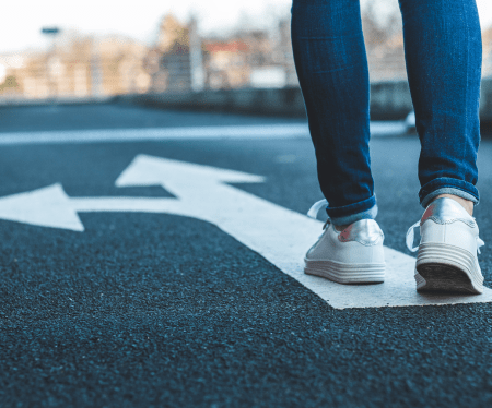 somebody walking on a road with a painted arrow